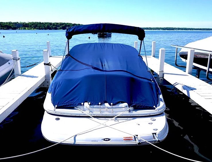 Boat with a blue custom cover docked at a marina